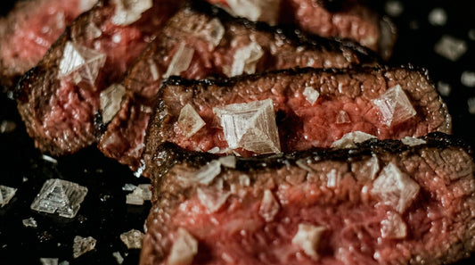 Hand streut Salz über Steak – richtiger Zeitpunkt für Finishing Salt